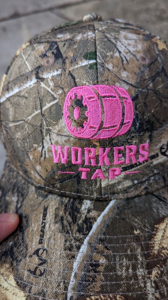 A workers tap hat in real tree camp with a pink logo