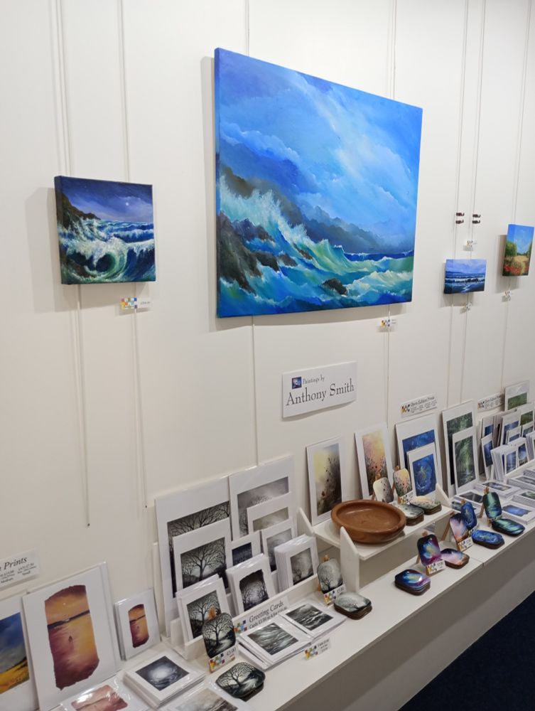 Left Wall of Gallery Anthony, Mullion, Cornwall 2025, Seascapes on the Back wall with prints, greeting cards and coasters on the shelf below