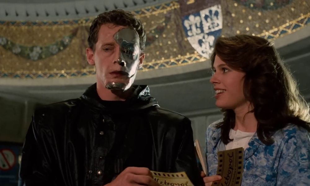 Shot from Demons (1985) where The Man in Black hands a ticket to a free showing of a horror film to the movie’s Final Girl.