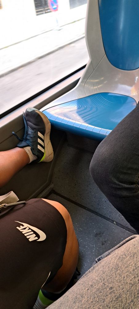 Tío poniendo un pie en un asiento de autobús de la EMT
