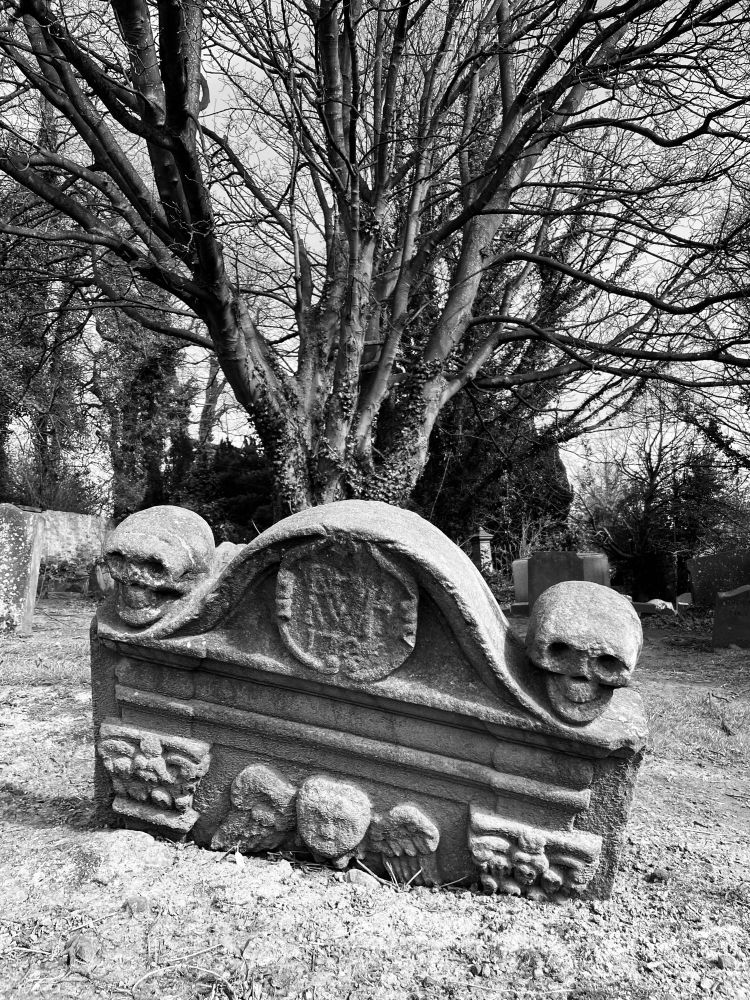 Couple of cheery skulls atop a headstone in the graveyard of Culross Abbey 