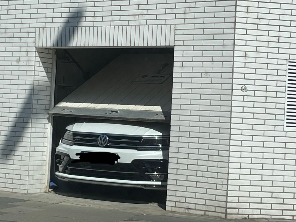 Zu großes Auto in zu kleiner Garage, so dass Garagentor auf Auto aufliegt. 