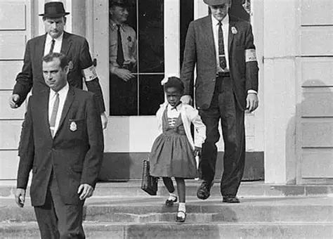 Photo de Ruby Bridges, première enfant afro-américaine à intégrer une école pour enfants blancs en 1960, à l'époque où la ségrégation scolaire prend officiellement fin aux États-Unis. Elle a alors 6 ans. Pour son premier jour d'école elle est escortée de policier et d'agents du FBI.
