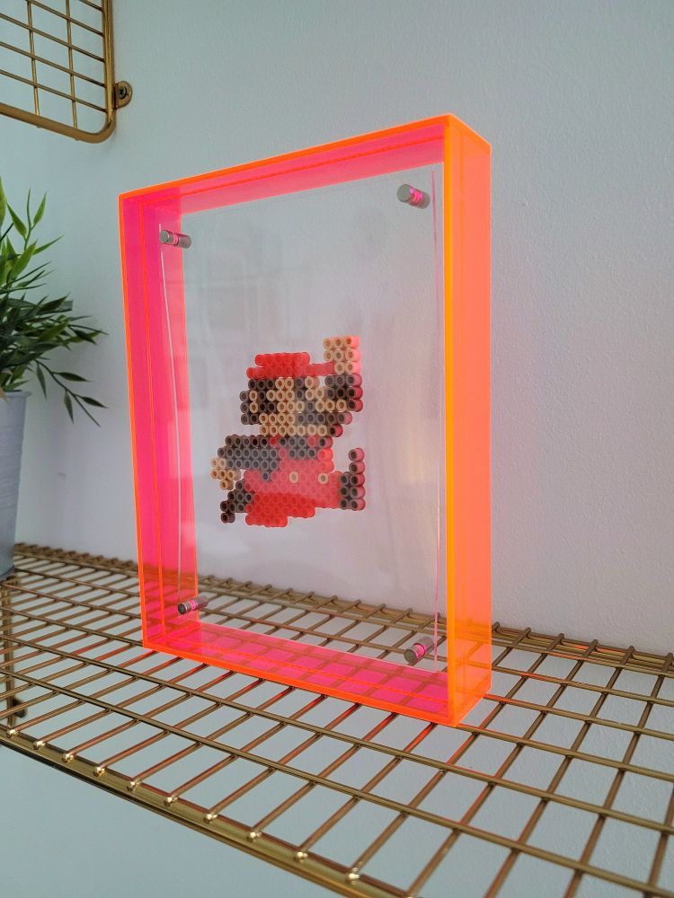 Pixel art sprite of Super Mario by @caveofpixels, suspended in a frame