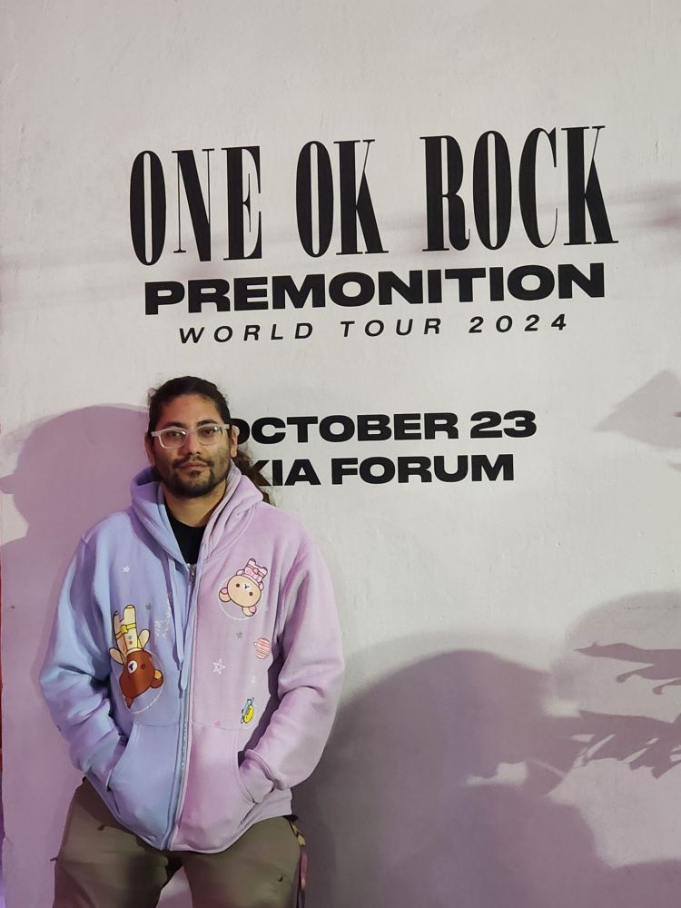 Man leaning on wall next to a band poster