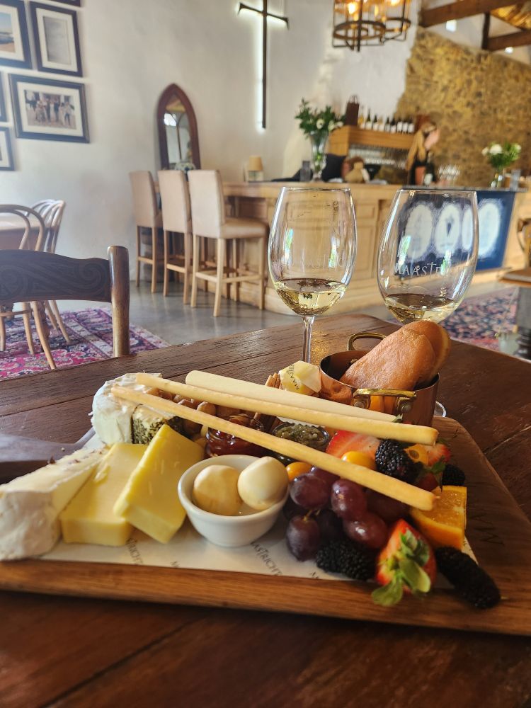 Loaded cheese board with two glasses of white wine 