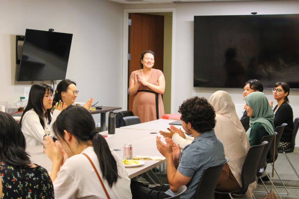 A photo of Asian American Federation staff standing and people sitting around a table and clapping.