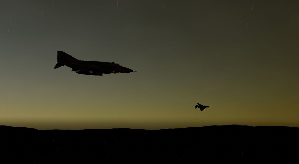 A 2-ship flight of F4 Phantom fighter planes silhouetted against a yellow dusk sky in tank sim game GHPC