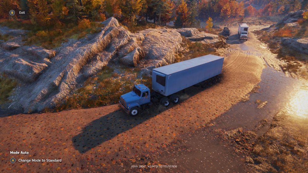 Two semi trucks traverse a washed-out road that has been hastily repaired with compacted soil. Screenshot from the game Roadcraft.