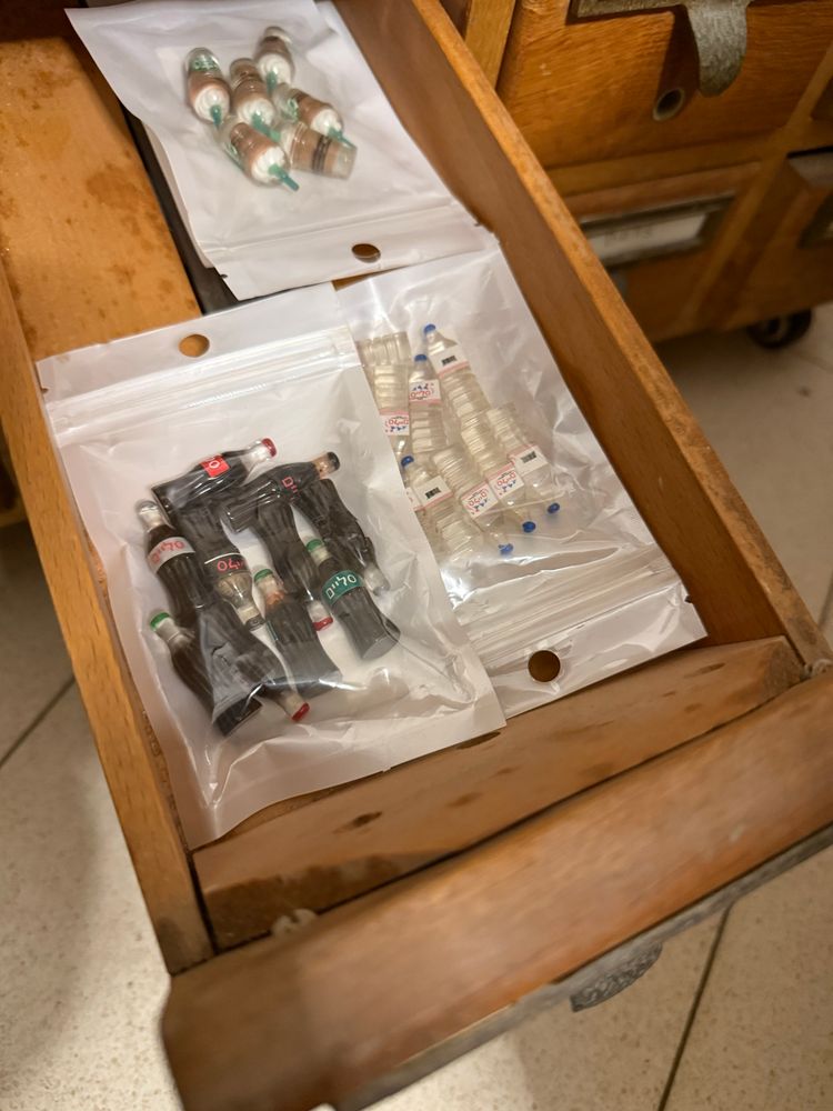 Drawer with little plastic bags containing miniature bottles of cola, water and cups of cold coffee drinks