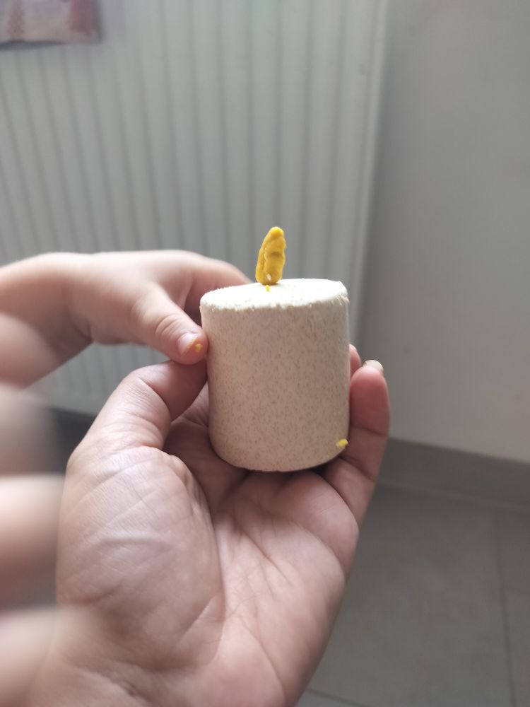 Bougie en pâte à modeler faite par Petite.
Je la tiens dans ma main, on voit la main potelée de petite qui la tient aussi.