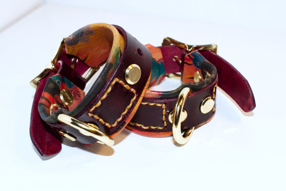 A pair of wine red leather cuffs with the butterfly floral backing. 