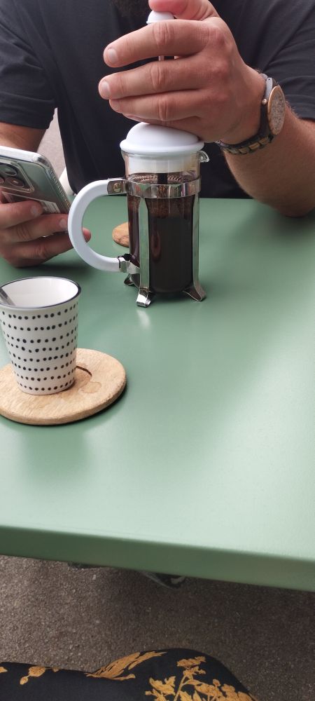 Table verte en ferraille avec deux micro tasses et un cafetière à piston au milieu 