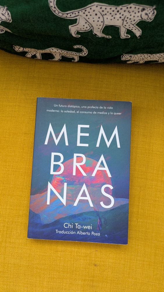 Portada del libro Membranas sobre un sofá amarillo. Ena portada apetece una cúpula en tonos rosas sobre un fondo azul.