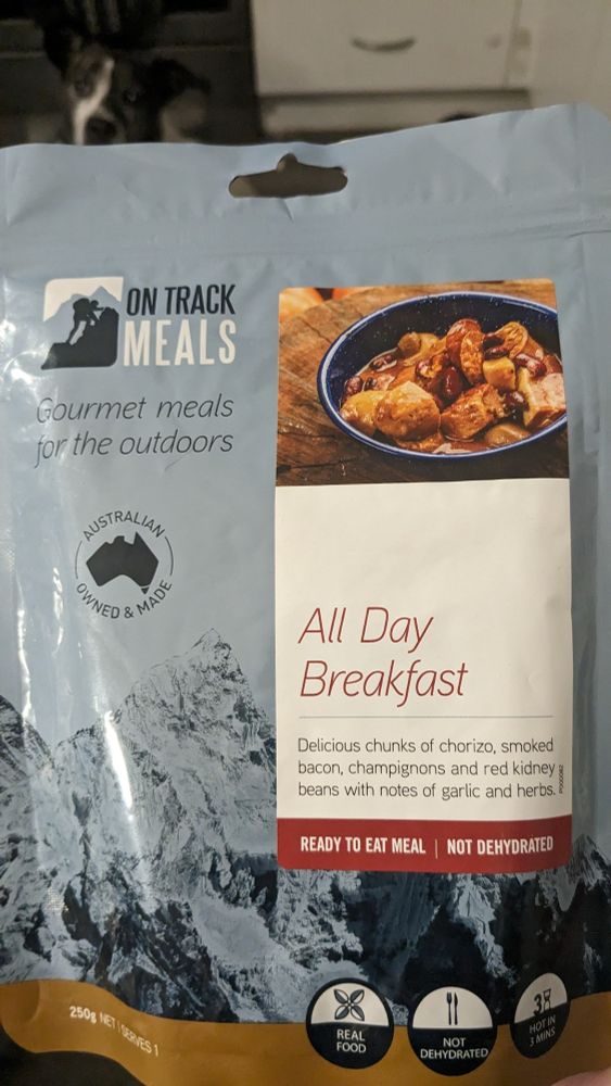 Photo of vacuum packed "gourmet outdoor meal" All Day Breakfast. Might contain something edible, might not. A small dog watches hopefully out of focus in the background.