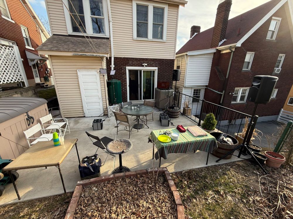 Back patio of house with chairs, tables, speakers, and air filters set up all around. 