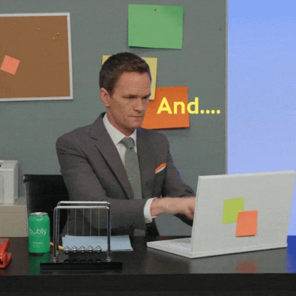 a man in a suit and tie is typing on a laptop with a can of bubbly in front of him