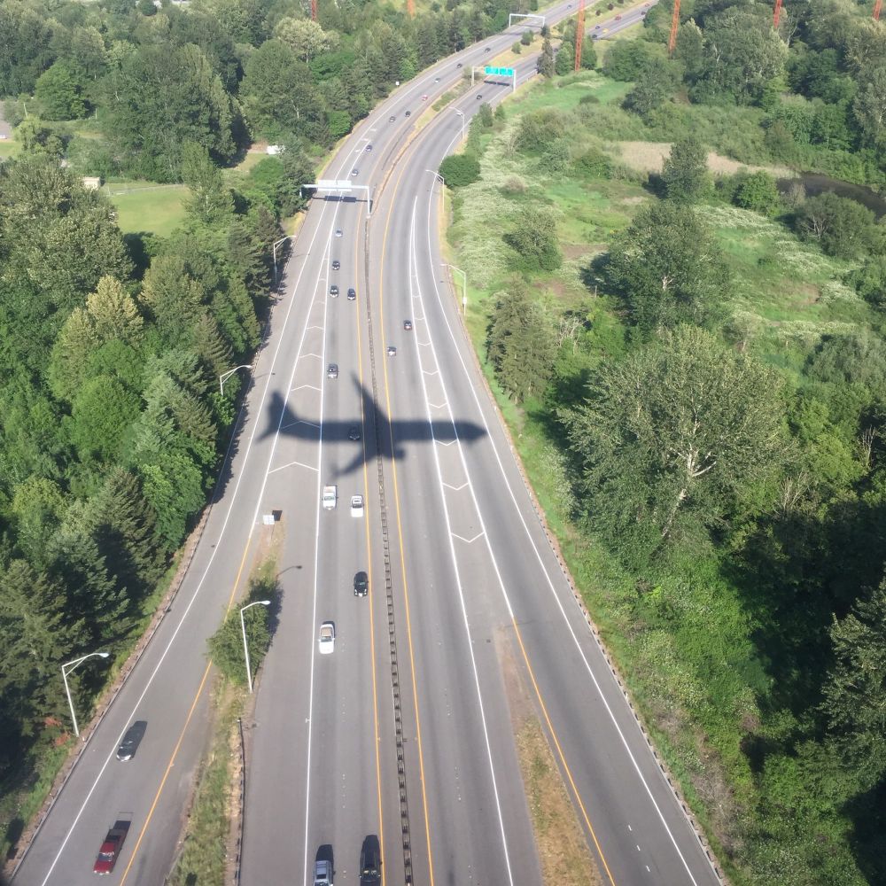 Silhouette of an airplane perfectly positioned over the center of a road as it lands
