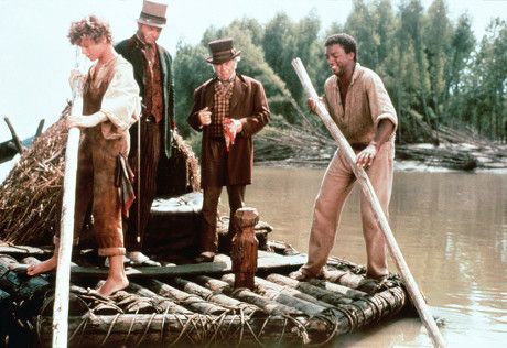 A still from Huckleberry Finn (1974) Huckleberry Finn (Jeff East) and Jim (Paul Winfield) push their raft along the river while The King (Harvey Korman) and The Duke (David Wayne) look on