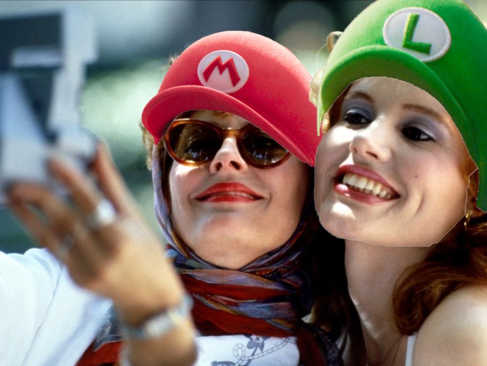 Still from Thelma & Louise of the title characters taking a selfie with a Polaroid camera, but with Mario & Luigi hats on them.
