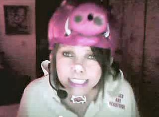 A grainy screencap of Hogville user LizHoney. She is wearing a Razorbacks foam hat, Razorbacks necklace, button that reads "Hogs are Beautiful, and has her nose scotchtaped to make her resemble a pig.