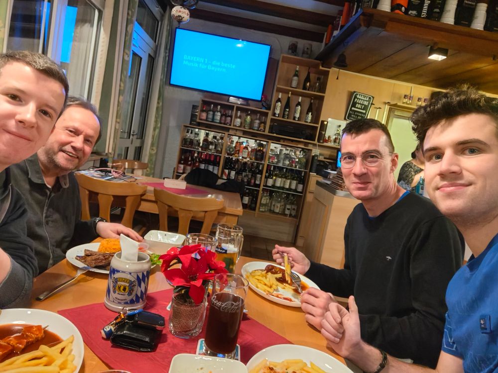 Vier Männer sitzen in einer Gaststätte und haben Spießen und Getränke vor sich. 