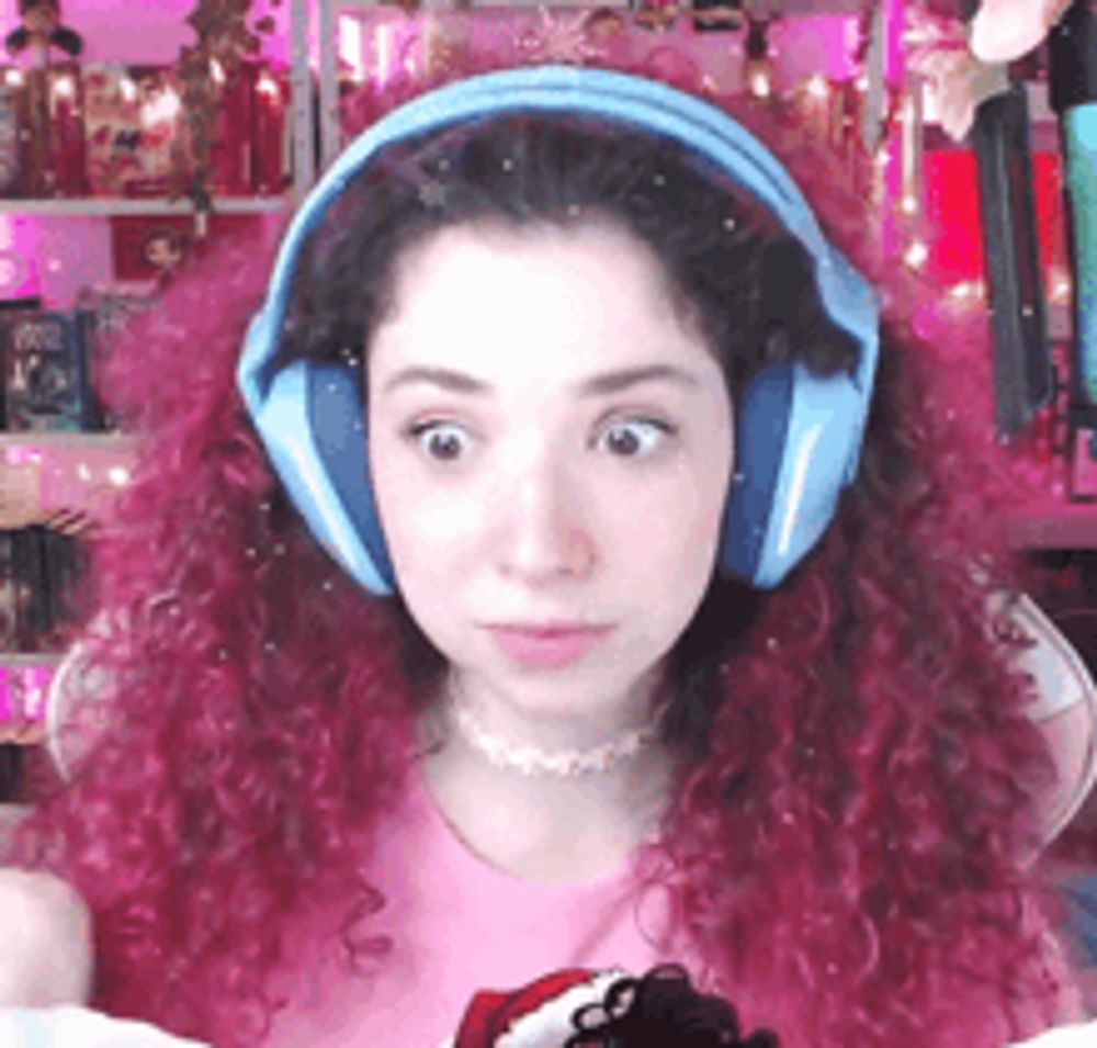 a girl with pink hair wearing headphones and a santa hat