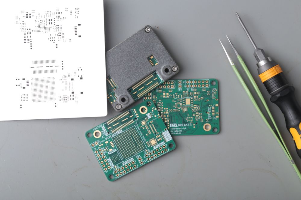 Circuit boards alongside a 3d printed enclosure, solder paste stencil and some tools.