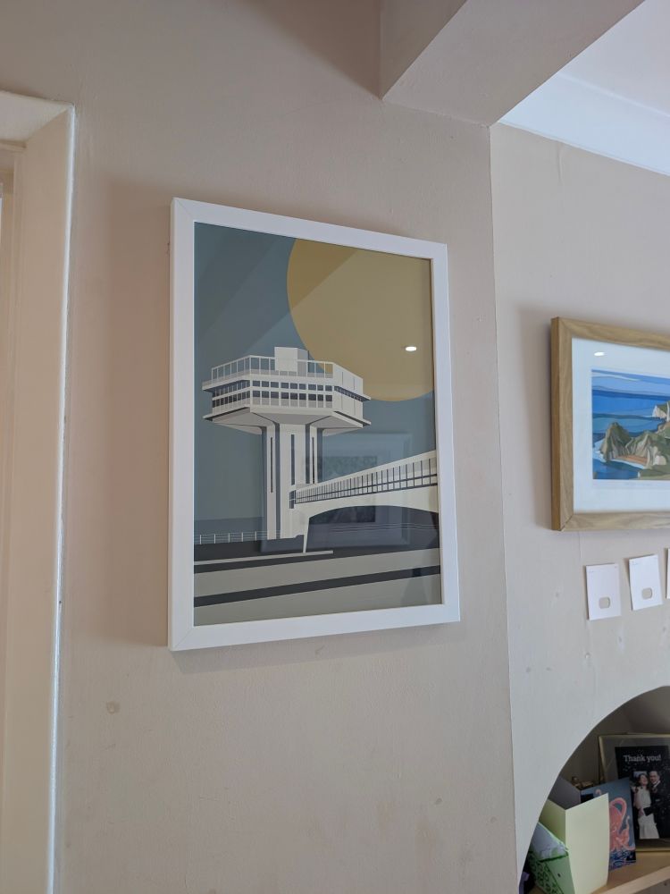 A print of the white tower at Forton motorway services, the one that used to spin and had a restaurant in it. A huge yellow sun is in the background of a teal sky, and the bridge stretches across the motorway in the foreground. It is a stylised, almost 60s style illustrative, graphic type image. 