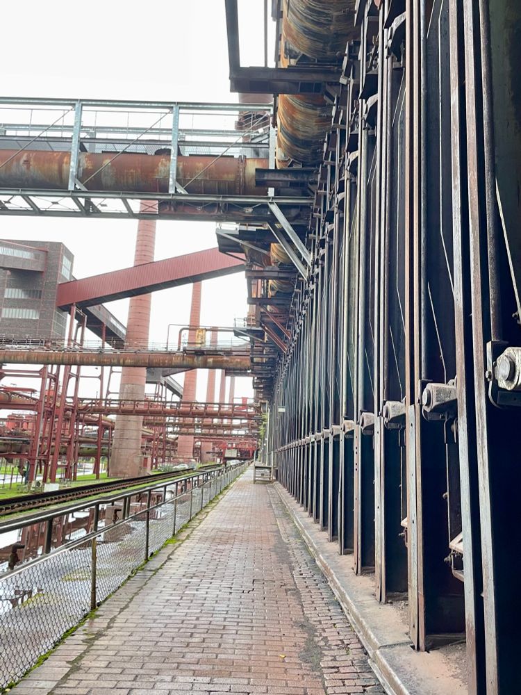 Eine alte Industrieanlage aus Backstein mit riesigen Schornsteinen, Förderbändern und etwa 500 4m x 8m Eisentüren