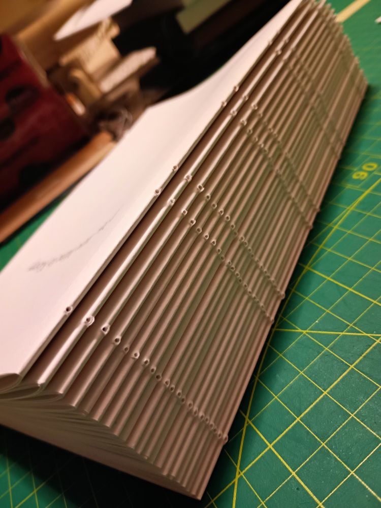 A stack of signatures ready to be sewn into a text block, showing all the pre-punched holes in the spine