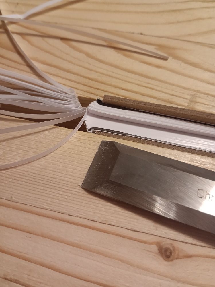 A partially trimmed little text block, between boards, posing with the chisel.