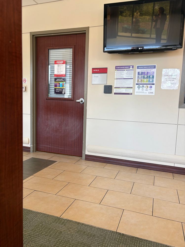 A photo of a nondescript interior hallway. The relevant detail is the sign next to the closed door that says “Triage”. Yuuuuup.