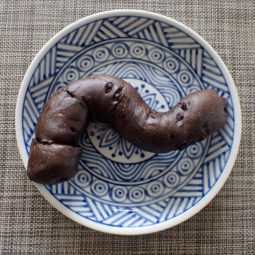 Brown, S-shaped bread with chocolate chips on a plate with blue & white geometric pattern.