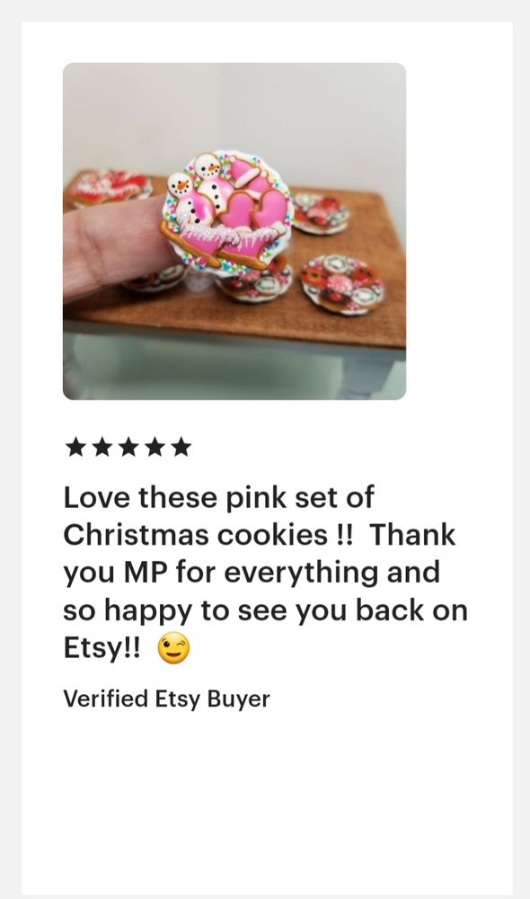 Review from Etsy. Picture of a finger holding a miniature plate of pink holiday cookies including sleighs, snowmen, mittens and hats. Underneath are 5 stars. "Love these pink set of Christmas cookies!! Thank you MP for everything and so happy to see you back on Etsy!!😉" 
Verified Etsy Buyer