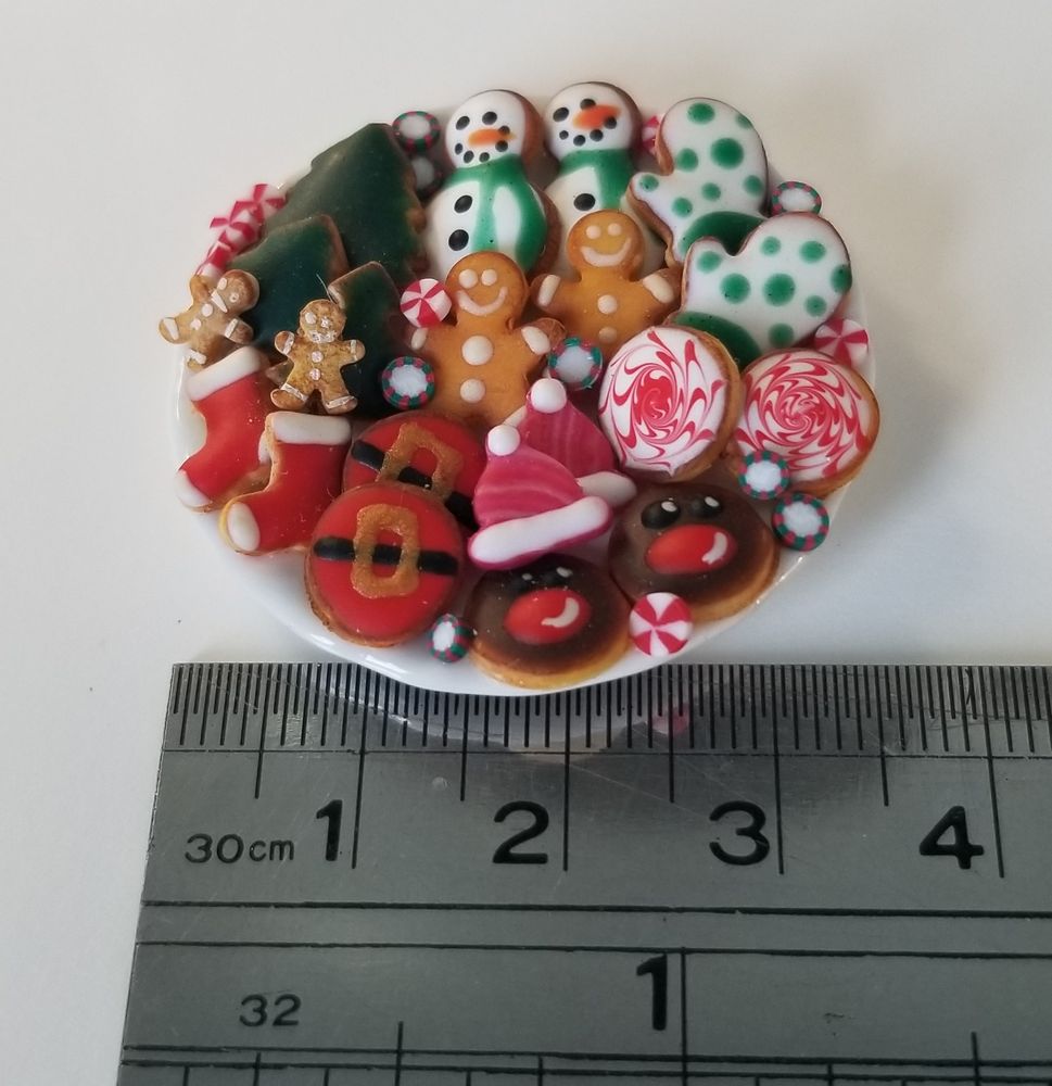 Miniature cookie plate including stockings, Santa belly, hats, Rudolph, peppermint rounds, gingerbread men, mittens, snowmen, and trees. Placed above a silver ruler showing size at 1-1/4 inch (3.5 cm)
