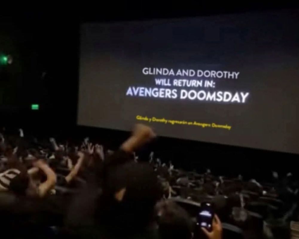 a very real picture of a movie theater screen that says "Glinda and Dorothy will return in: Avengers Doomsday"