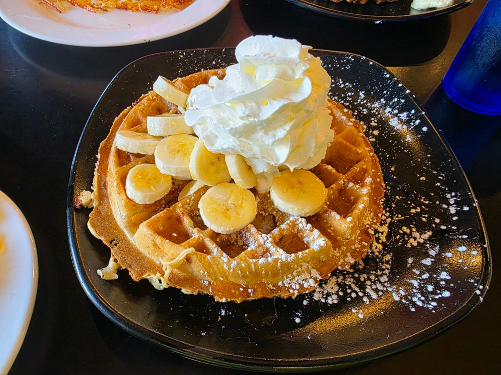 a waffle with banana slices and whipped cream 