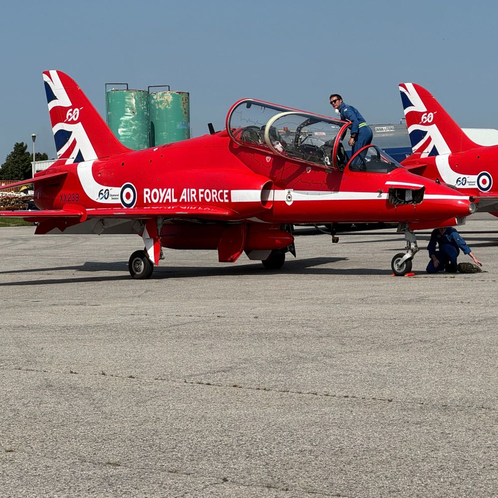 Maintenance 'Blue Crew' cleaning the canopy of a red arrow Hawk jet.