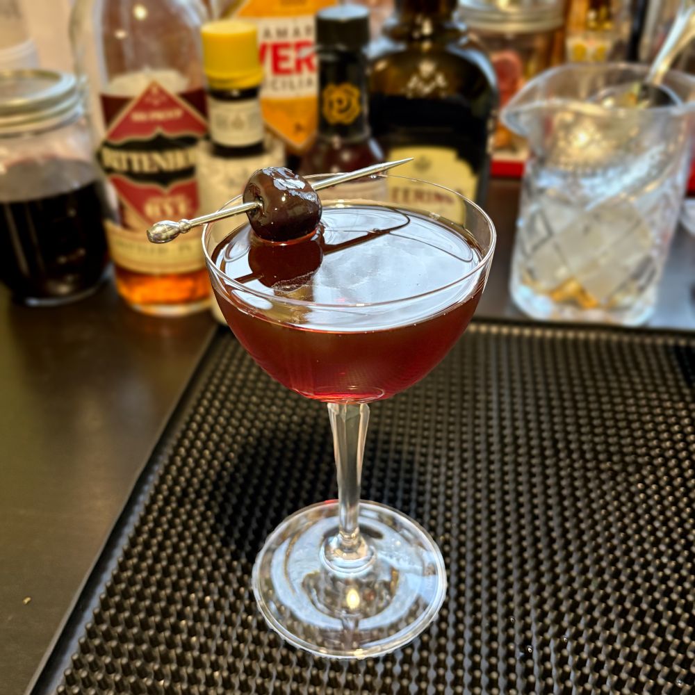 Red-brown cocktail in a stemmed glass. 