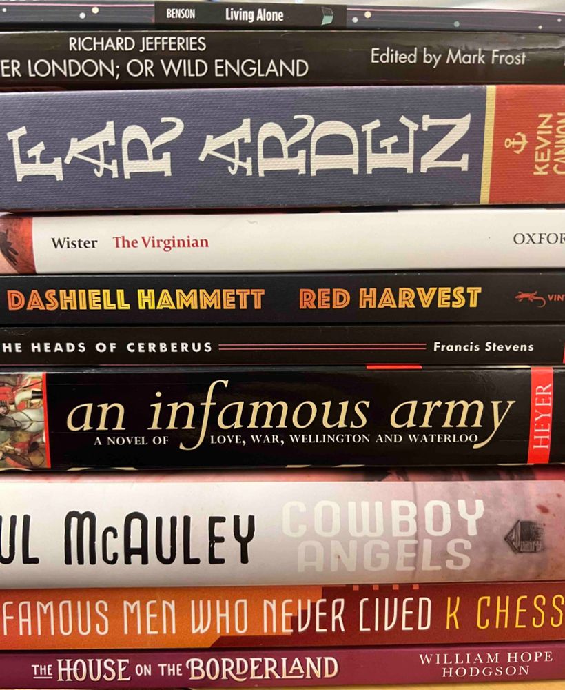 A photograph of the spines of the following books: The House on the Borderland, Famous Men Who Never Lived, Cowboy Angels, An Infamous Army, The Heads of Cerberus, Red Harvest, The Virginian, Far Arden, After London, and Living Alone.