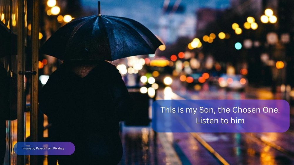 A rainy city street, with street lights reflected on the wet road. In the foreground there is a back view of someone in a black coat holding an umbrella. The text reads: “This is my Son, the Chosen One. Listen to him.”