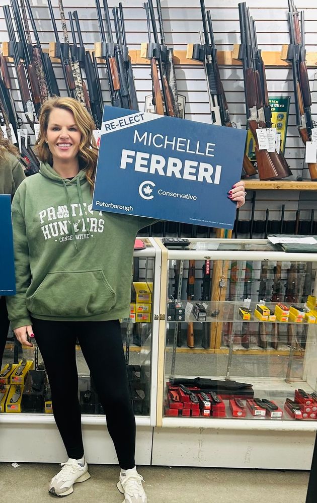 Conservative MP Michelle Ferreri poses in a gun shop with one of her election signs