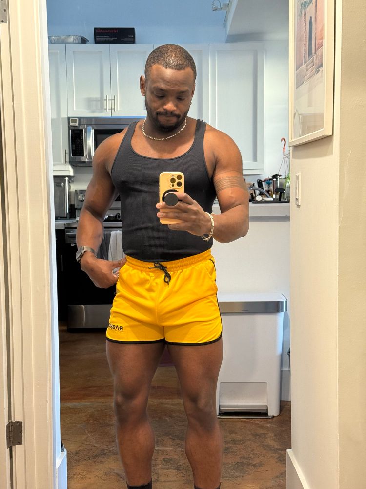 a mirror pic of me with my gym fit. yellow short shorts and a black tank. very original