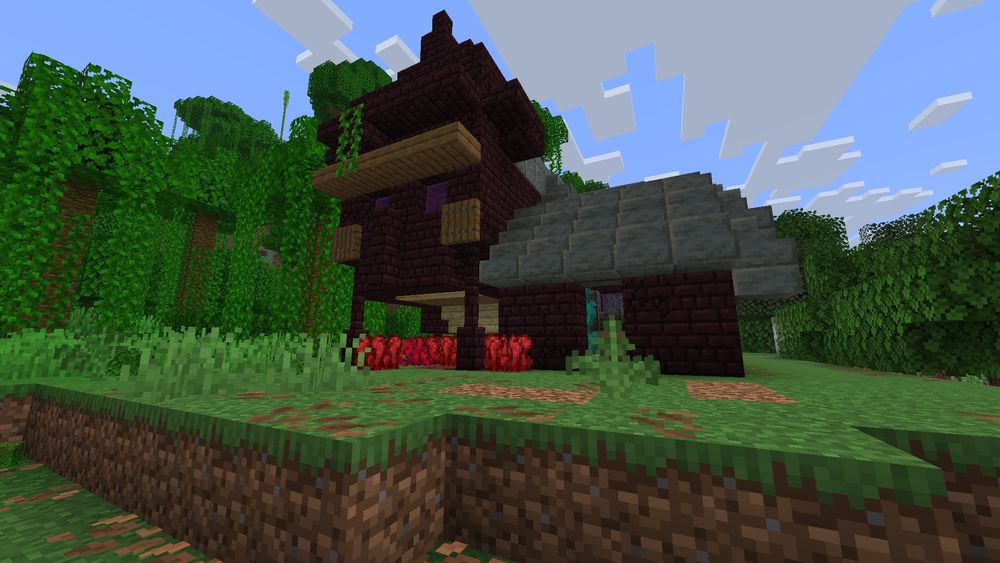 A picture of a building made of dark red brick (Nether Brick) and light gray (polished tuff). On one side is a low doorway, on the other is a wall that has been shaped to resemble the Witch mob's face, complete with a long nose, a stern eyebrow, and long hat. Red, fungus like foliage is growing underneath that section.