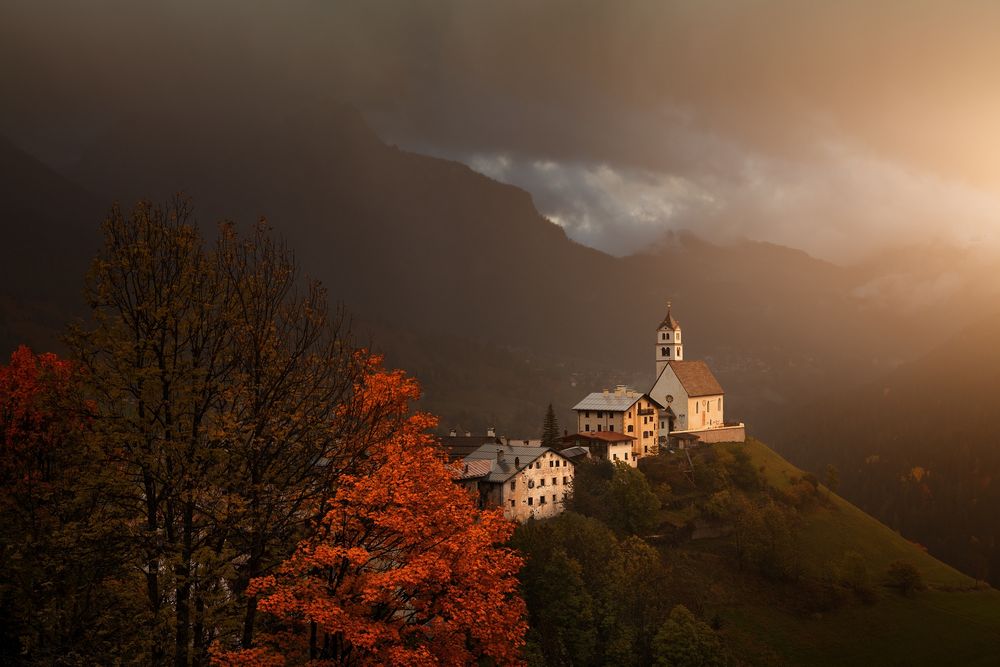 View of an alpine church in the Dolomites during a rainy autumn day, when the evening light briefly shone on the church.