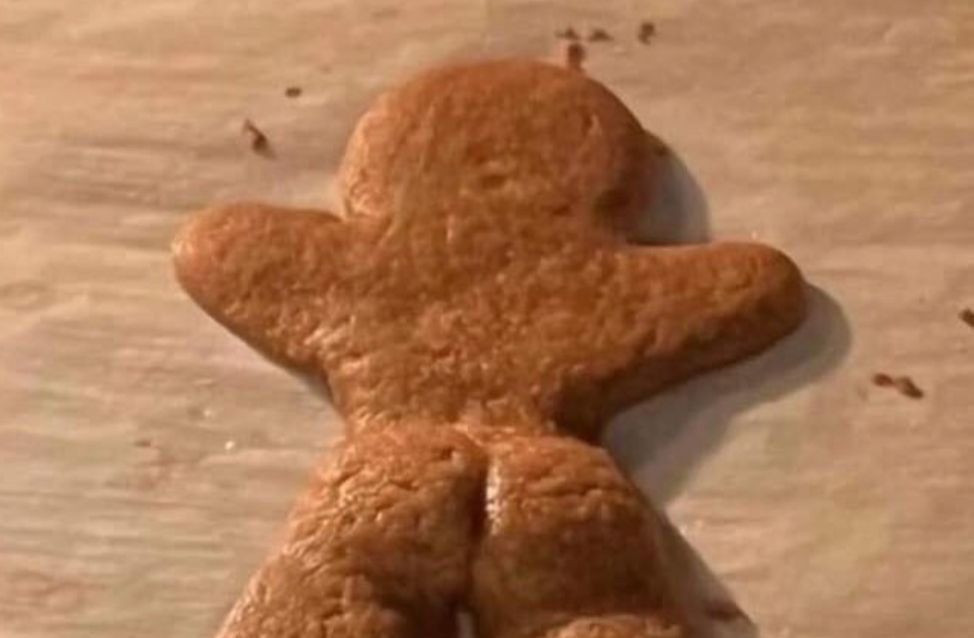 Photo of a very caked up gingerbread person laying on a baking sheet.