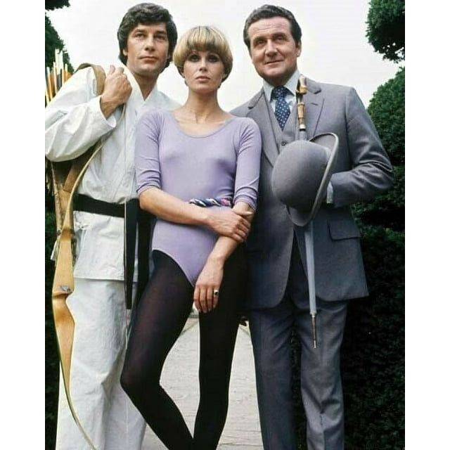 The New Avengers (1976-1977)

Gareth Hunt as Mike gambit, here seen wearing a karate gi and carrying a bow and arrows. 
Joanna Lumley as Purdey, wearing a leotard and leggings. 
Patrick MacNee as John Steed, in his customary suit with bowler hat and umbrella