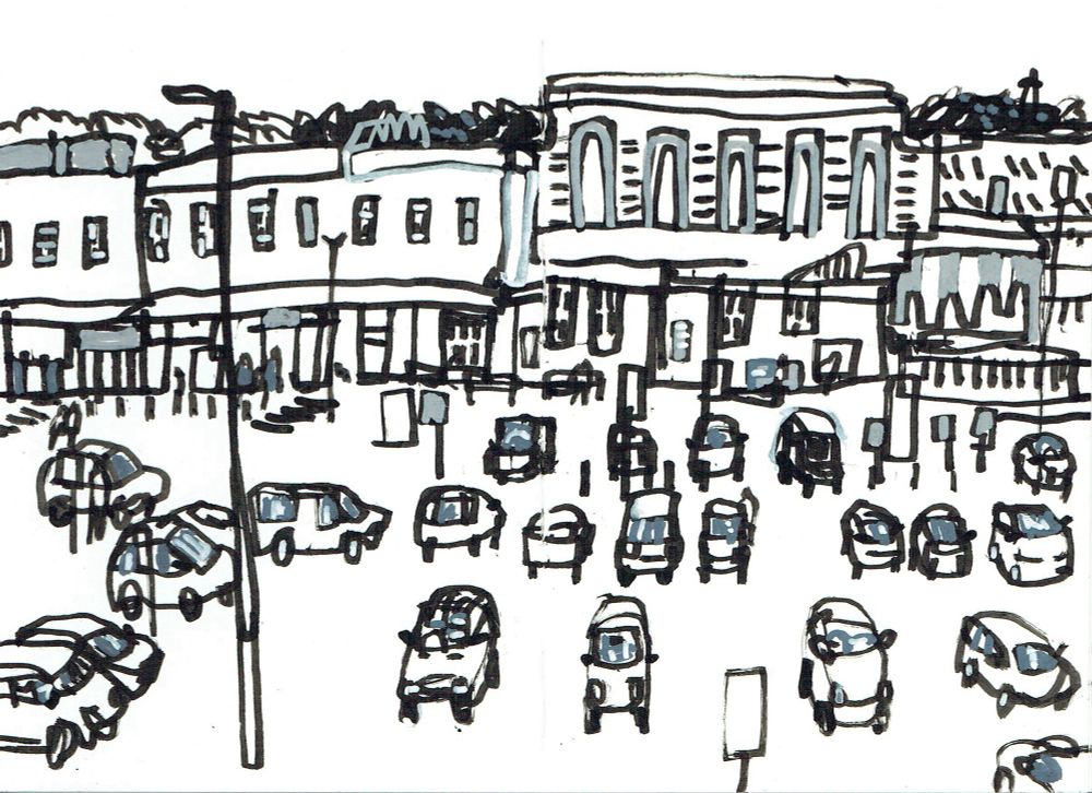 A drawing in black ink showing a car park in front of a railway station, with a glimpse of Devon’s rolling hills behind. 