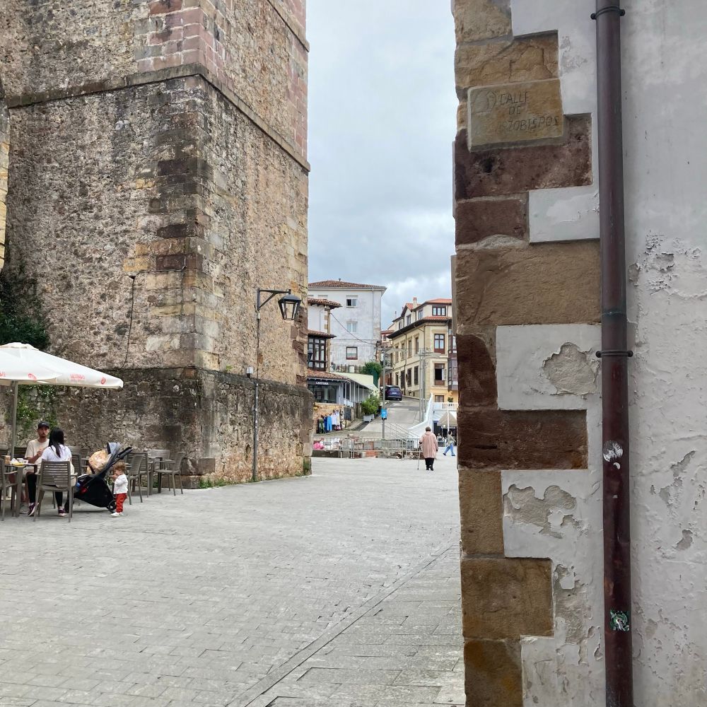 A glimpse of a Spanish town scene between two buildings, one close, one further back.